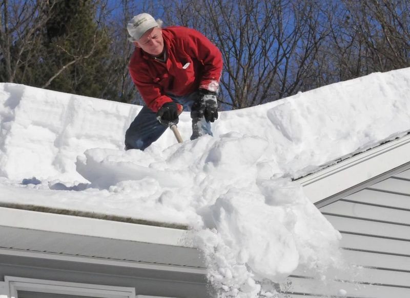 Мужчина чистит крышу от снега